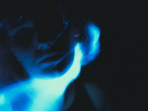 Silhouette of a woman meditating with a vibrant blue aura.